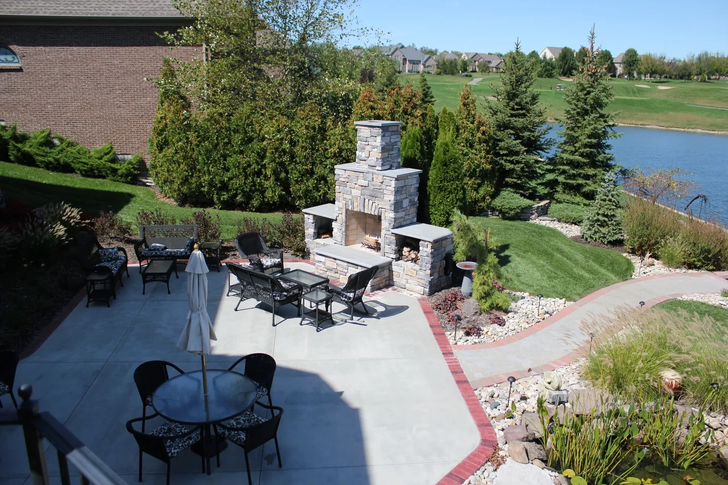 A patio with tables, chairs and an outdoor fireplace.