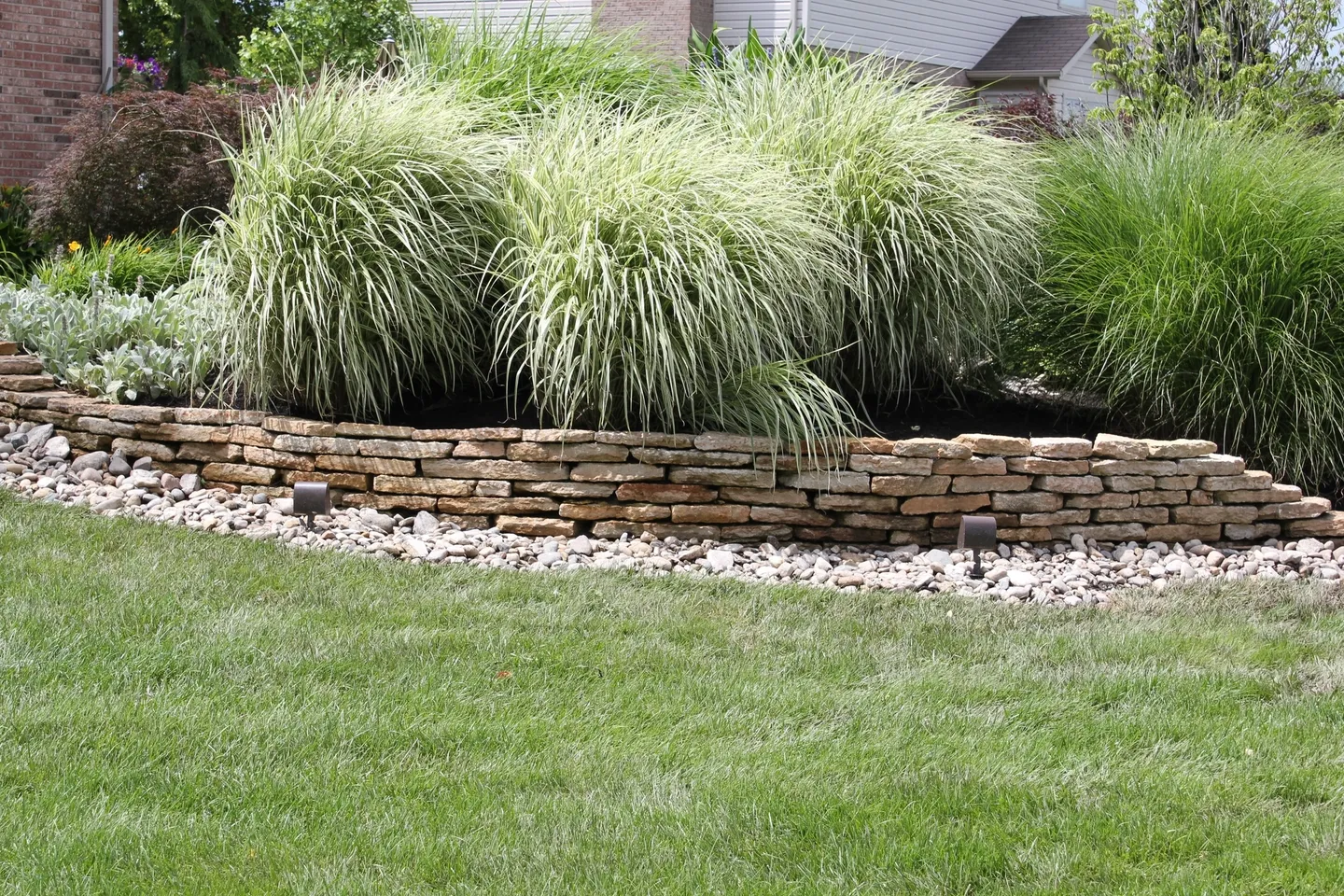 A stone wall in the middle of a yard.
