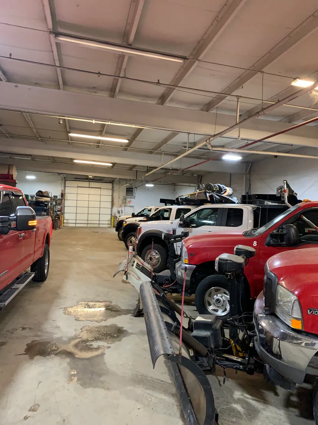 A group of trucks in a garage with lots of vehicles.